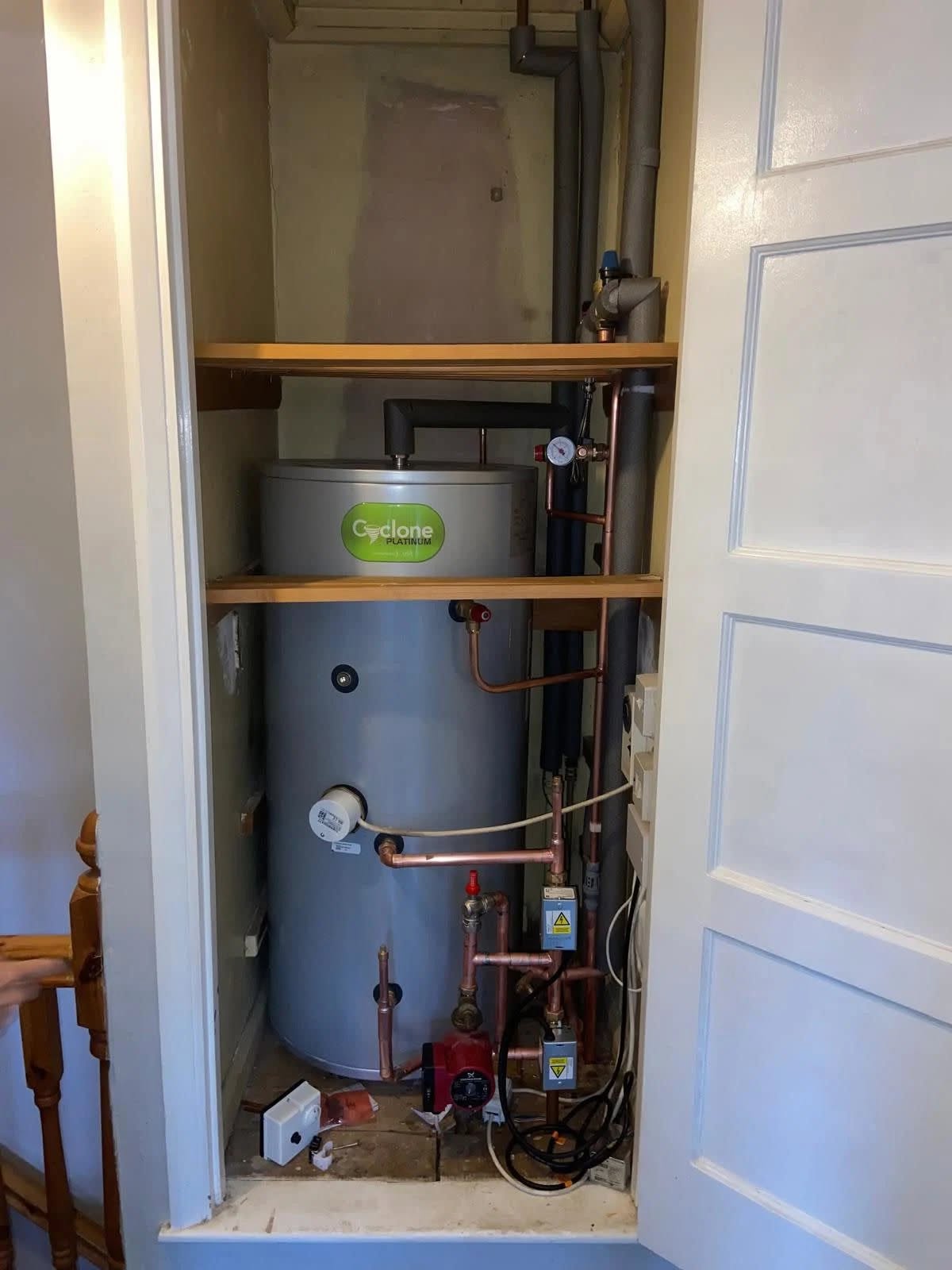 A new grey cylinder fitted in a cupboard with timber shelves