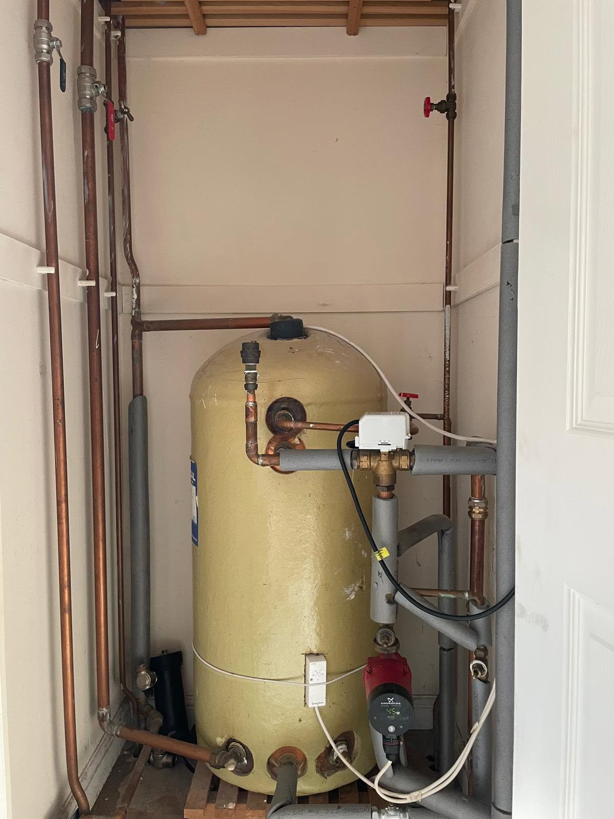 An old copper hot water cylinder in an airing cupboard, before the work