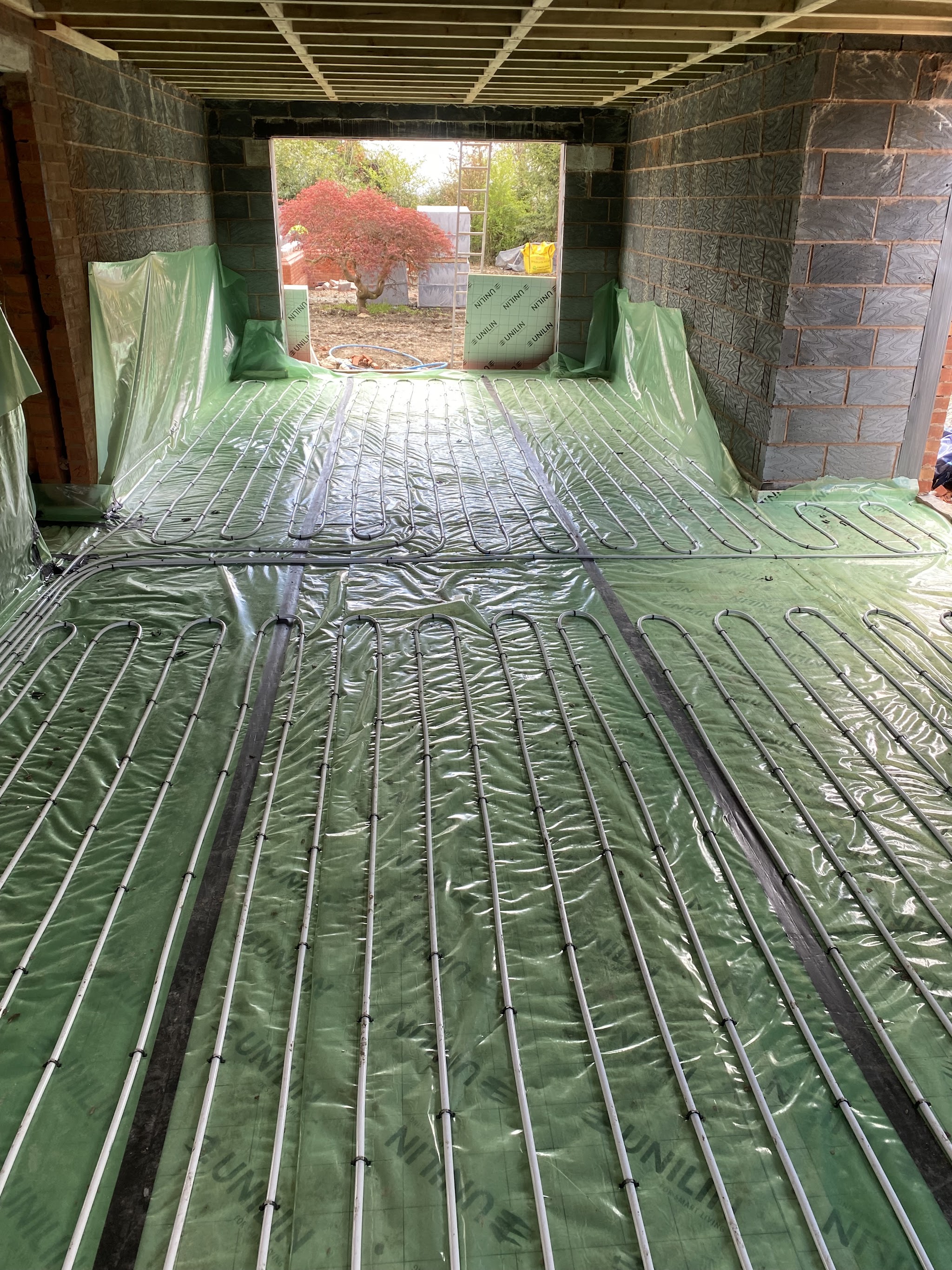 Underfloor heating loops on green membrane in a long extension open to the garden